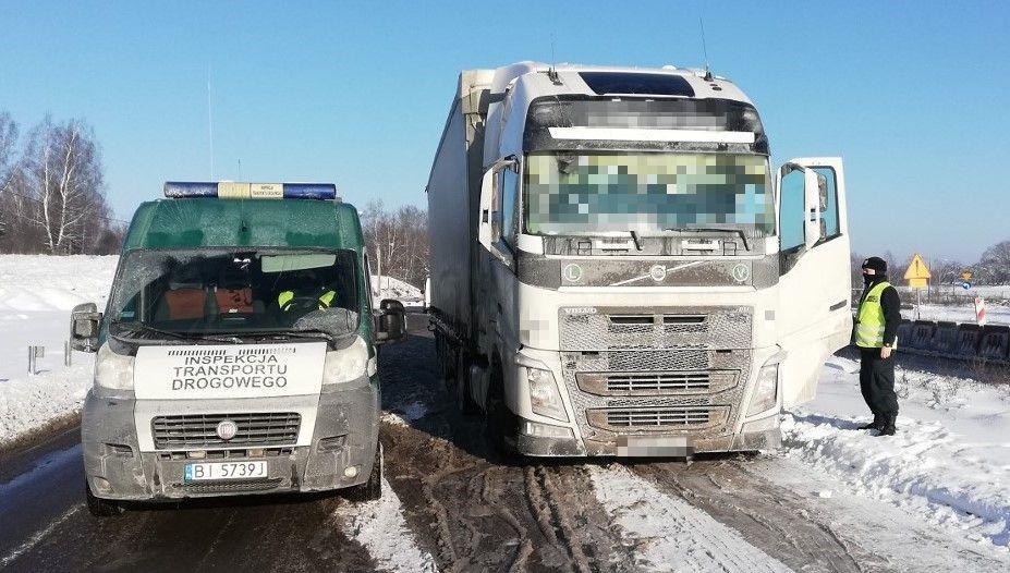 Inspektor stoi koło kabiny ciężarówki i kontroluje kierowcę.