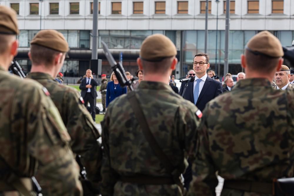Widok na żołnierzy, a za nimi stoi premier Mateusz Morawiecki.