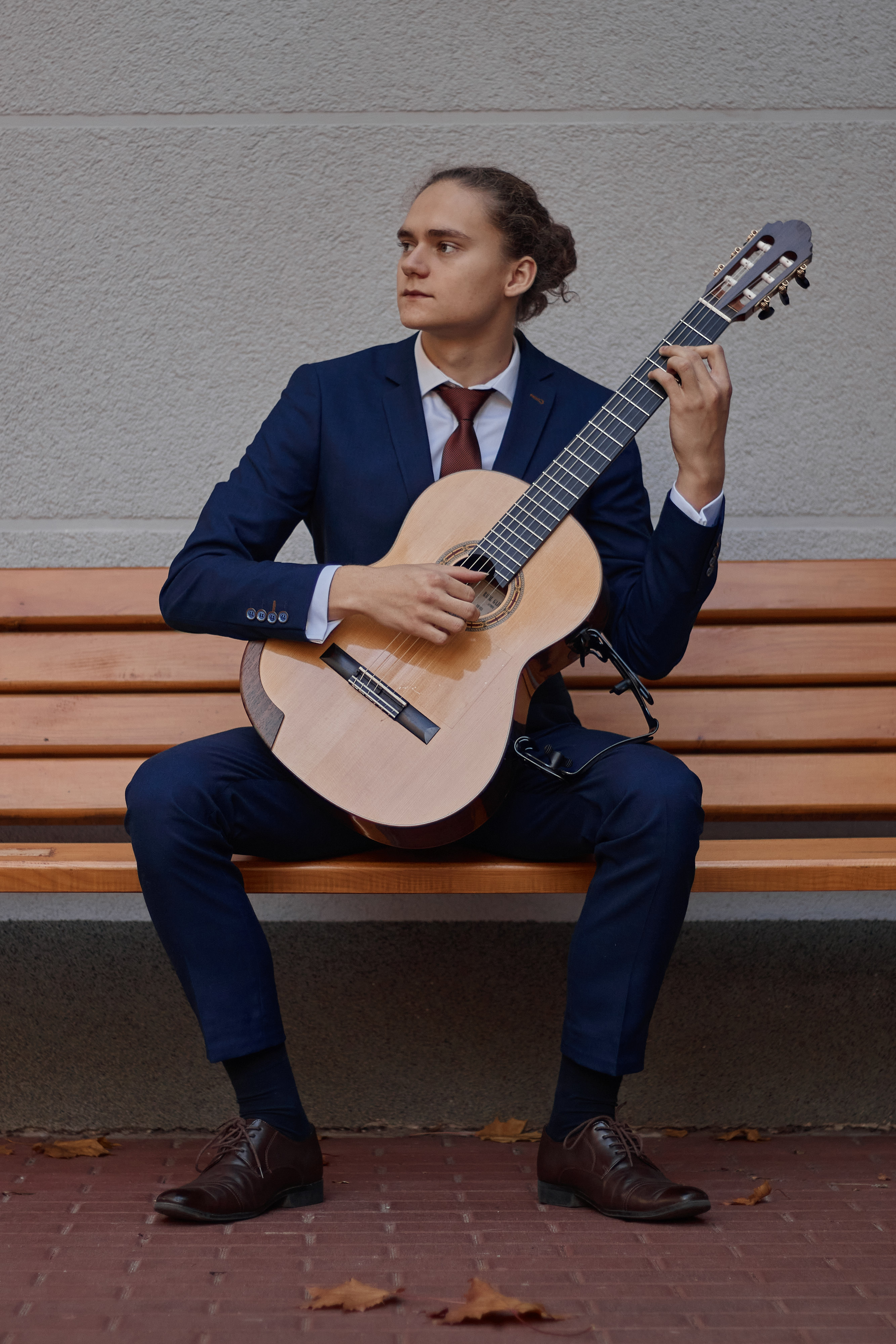 Na zdjęciu Matusz Wójcik z gitarą siedzący na ławce.
