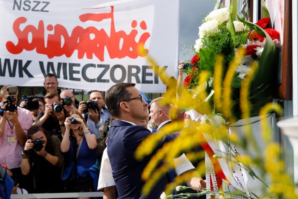 Premier Mateusz Morawiecki składa kwiaty przed Bramą nr 2 w Stoczni Gdańskiej, w tle napis "Solidarność".