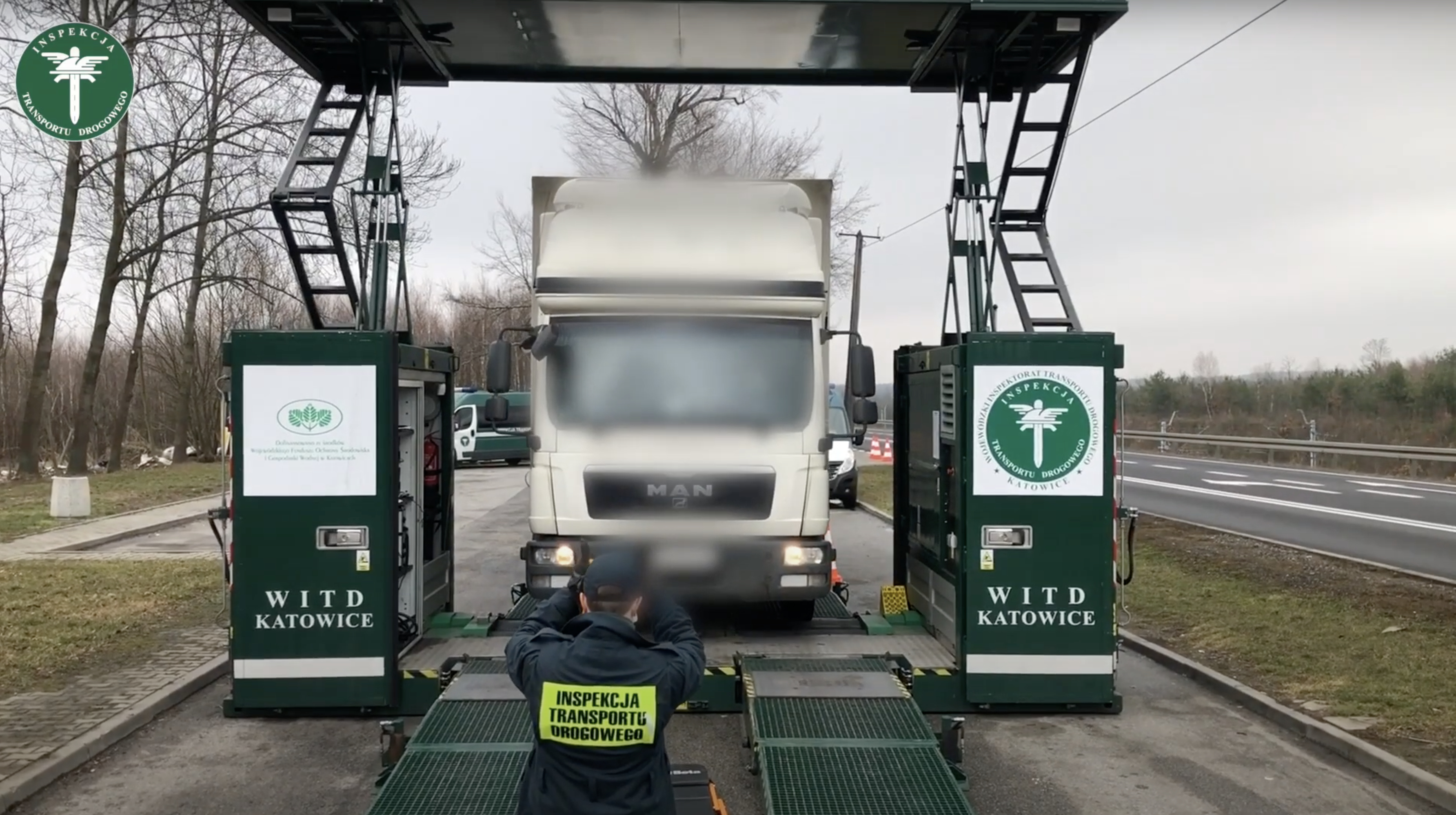 Inspektor śląskiej ITD kieruje zatrzymaną ciężarówkę na mobilną linię diagnostyczną.