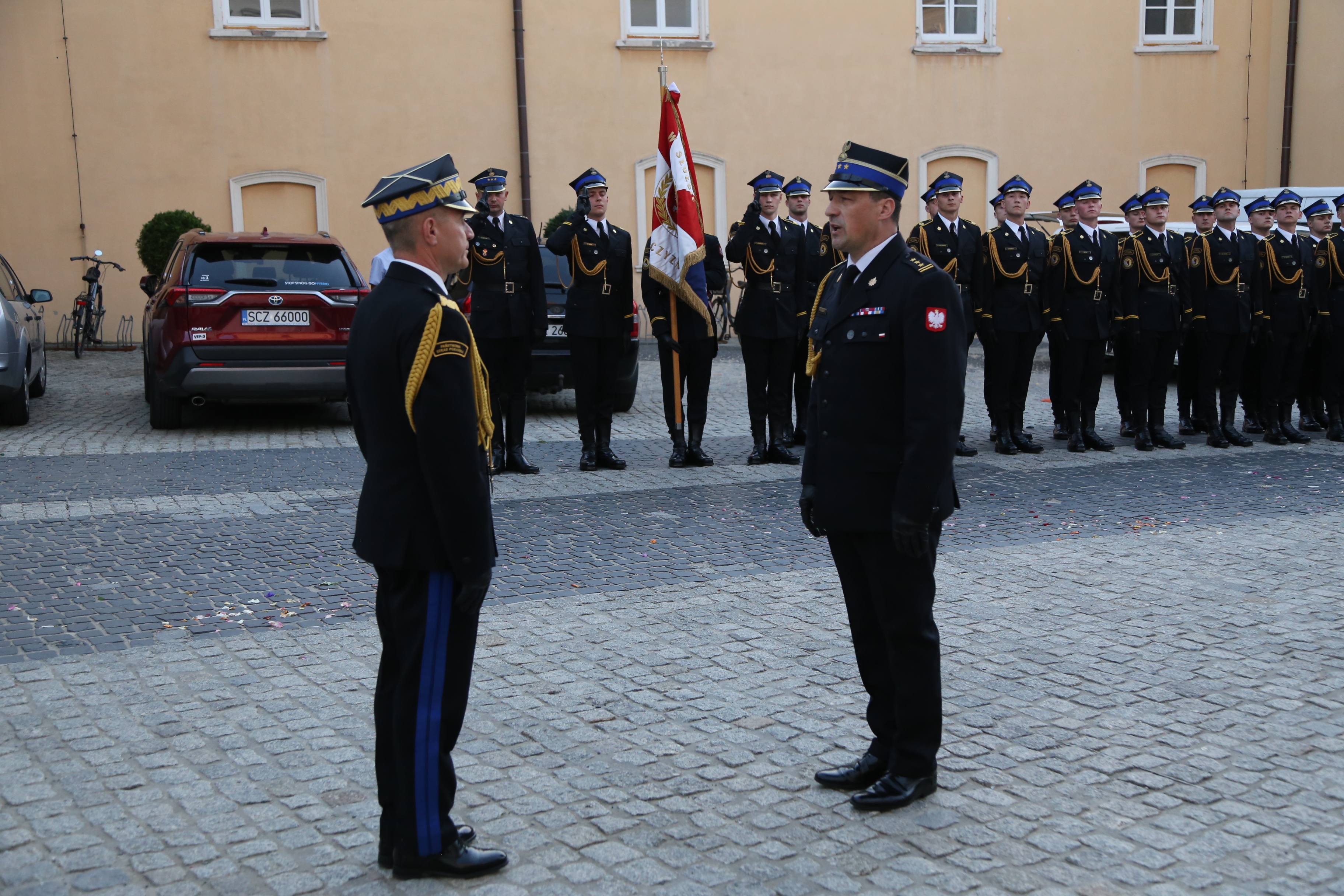 Komendant CS PSP w Częstochowie składa meldunek komendantowi głównemu PSP, w tle w dwuszeregu ustawieni strażacy w mundurach galowych