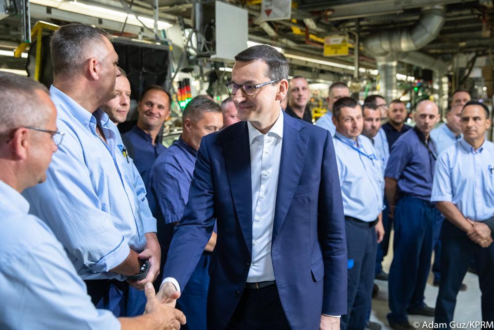Premier Mateusz Morawiecki wita się z pracownikami fabryki Opla.