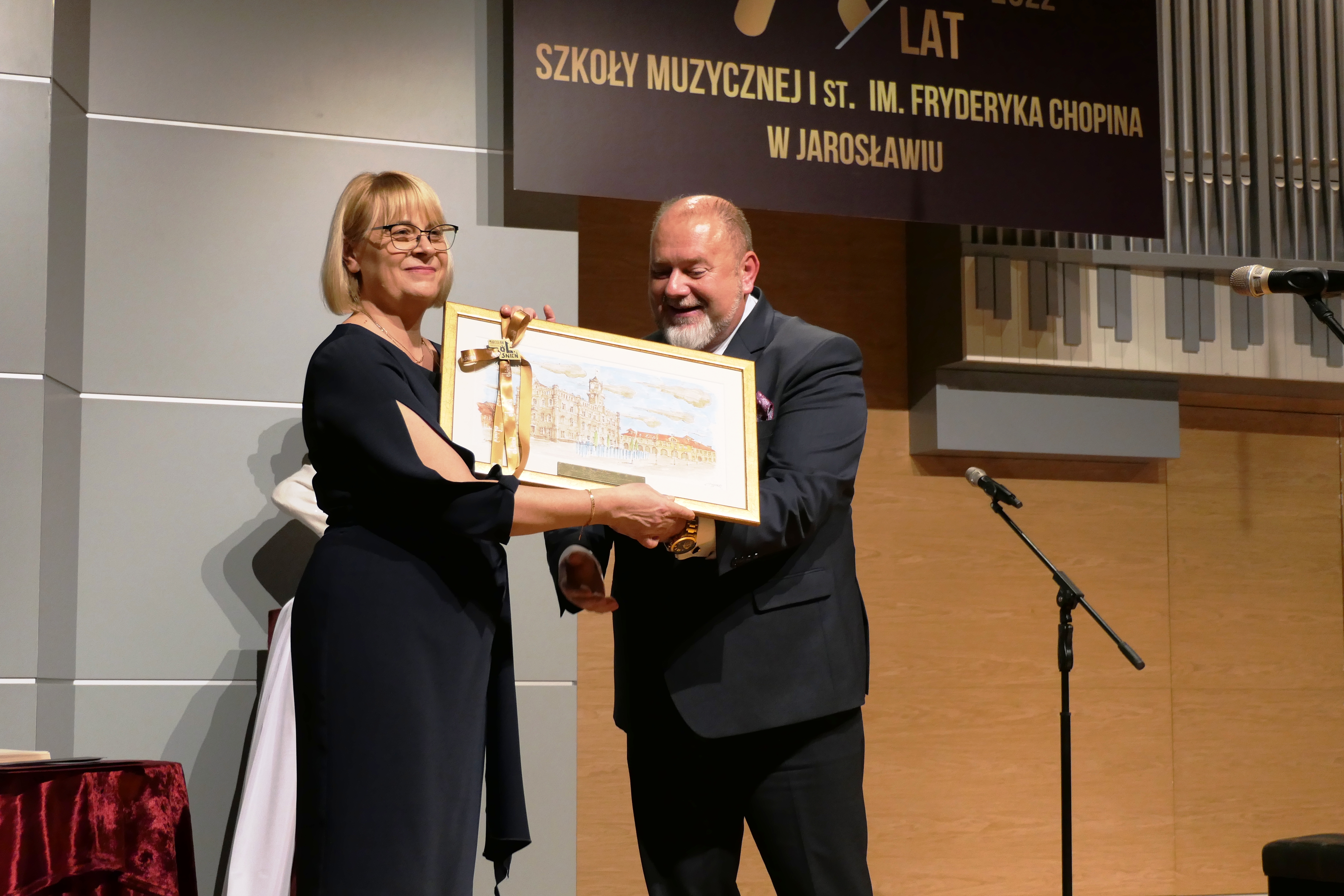 Zdjęcie przedstawiające stojących na scenie sali koncertowej Grażynę Seredę - dyrektor ZPSM im. F. Chopina w Jarosławiu oraz Waldemara Palucha - Burmistrz Miasta Jarosławia
