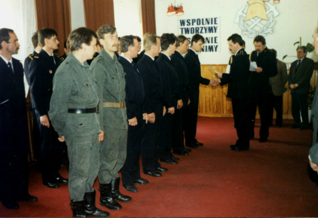 Dzień Strażaka lata 90 XX w. Strażacy w umundurowaniach podczas uroczystego apelu wewnątrz starej komendy Zawodowej Straży Pożarnej w Limanowej. 