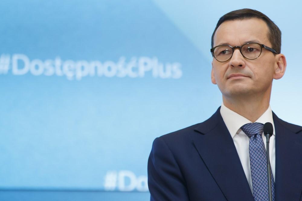 Premier Mateusz Morawiecki, a w tle ścianka wizyjna z #DostępnośćPlus.