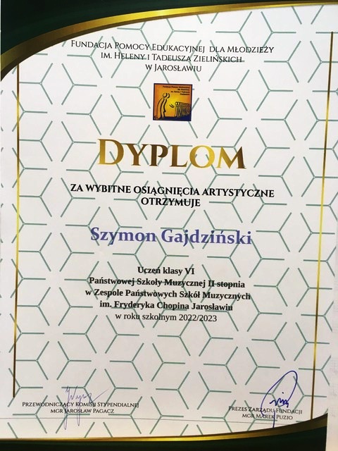 Dyplom na ozdobnym tle, ze stylizowaną na otwieraną kartę książki grafiką. Na górze napis FUNDACJA POMOCY EDUKACYJNEJ DLA MŁODZIEŻY IM. HELENY I TADEUSZA ZIELIŃSKICH W JAROSŁAWIU. Poniżej logotyp fundacji i złoty napis dużymi literami DYPLOM za wybitne osiągnięcia artystyczne otrzymuje Szymon Gajdziński Uczeń kl. VI PSM II st. w ZPSM im. F. Chopina w Jarosławiu w roku szkolnym 2022/2023