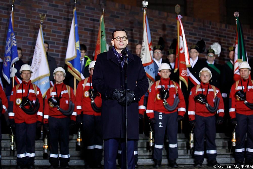 Premier Mateusz Morawiecki stoi podczas przemówienia.