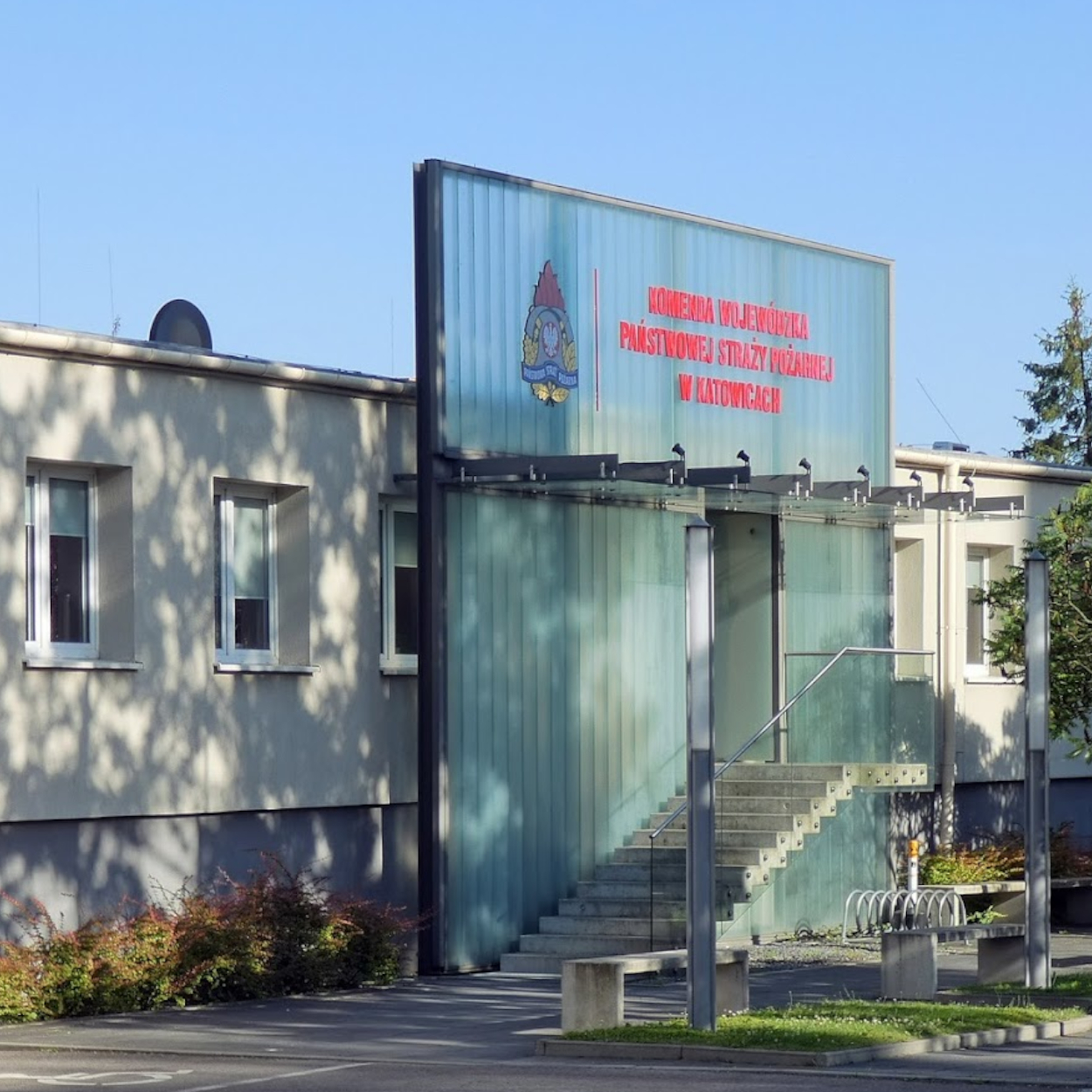 Zdjęcie przedstawia wejście do budynku Komendy Wojewódzkiej PSP. widoczne schody weściowe i okna w budynku.