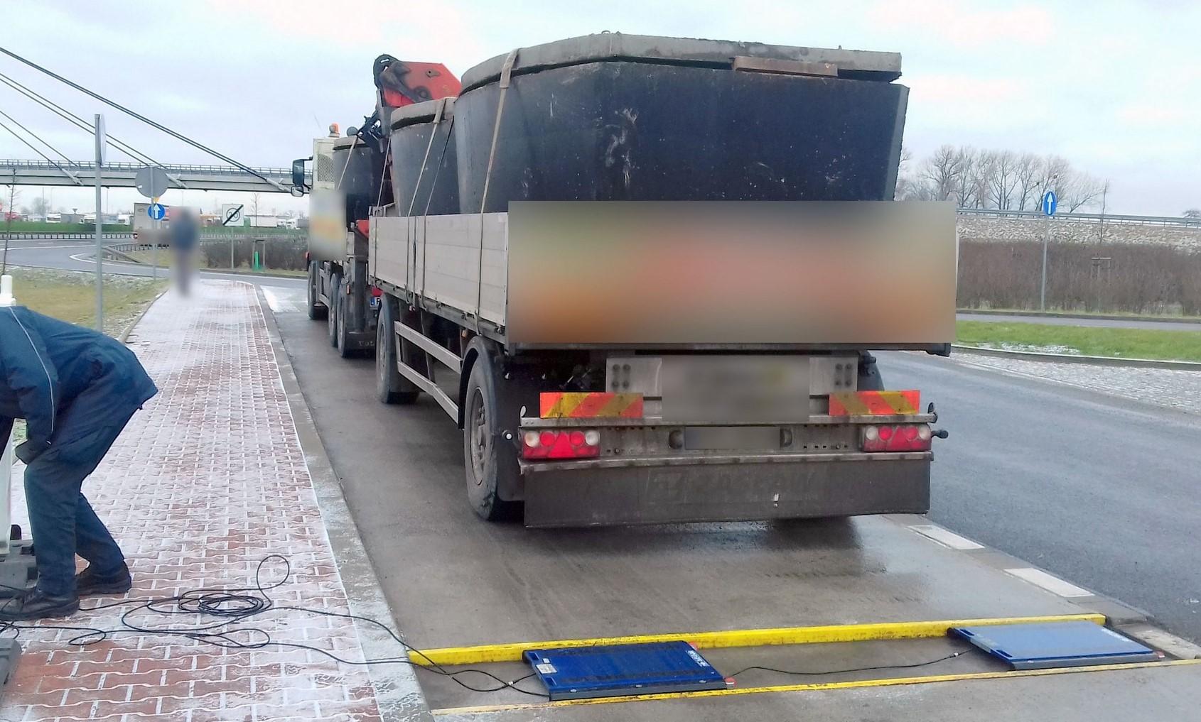 Przenośne wagi ITD i przeładowana ciężarówka z szambami betonowymi.