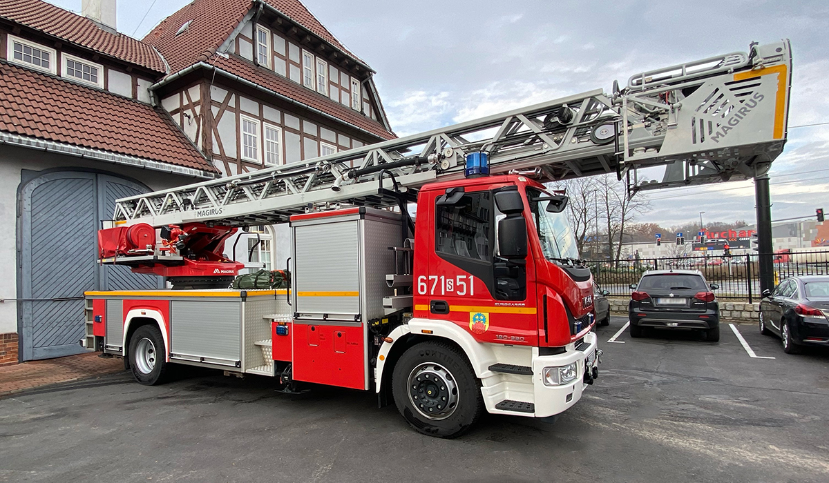Zdjęcie przedstawia samochód specjalny z drabiną mechaniczną Iveco Magirus na tle budynku Komendy Miejskiej Państwowej Straży Pożarnej w Zabrzu