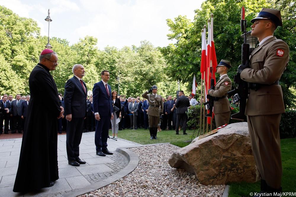 Premier Mateusz Morawiecki, Antoni Macierewicz i biskup Michał Janocha stoją przed kamieniem węgielnym.