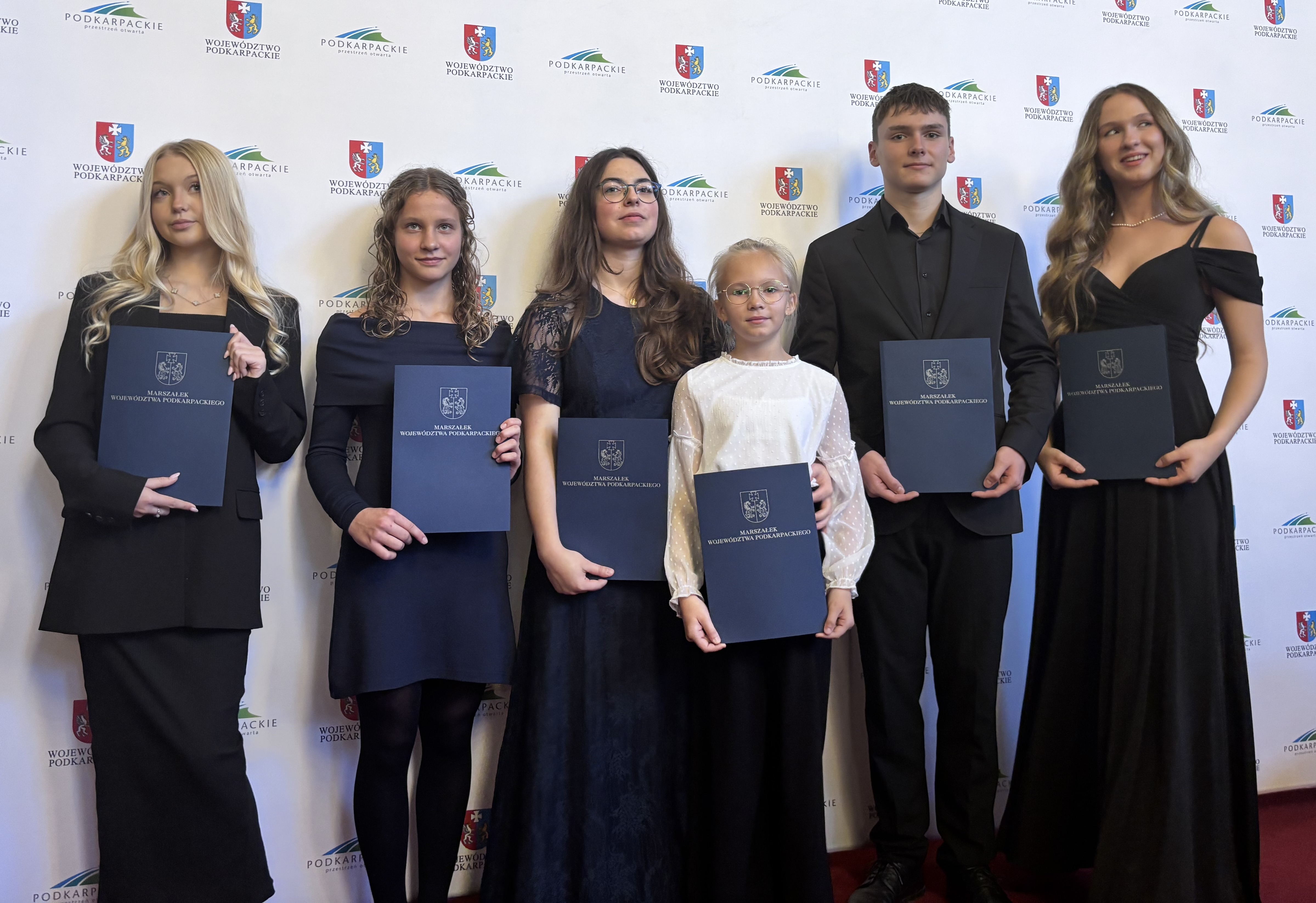 Laureaci stypendiów "Nie zagubić talentu". Laureaci na tle baneru z logami organizatorów.