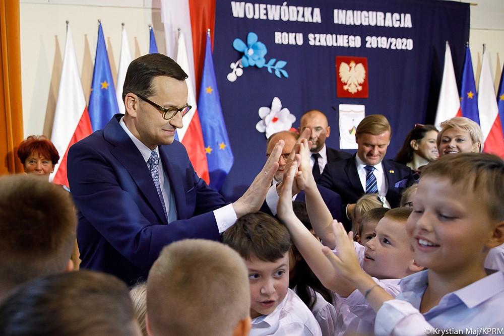 Premier Mateusz Morawiecki przybija piątkę z uczniami.