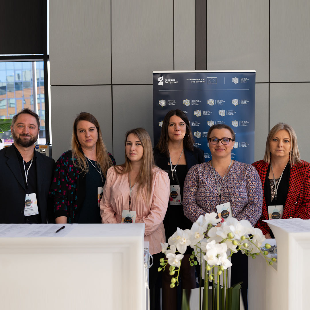 Uczestnicy konferencji - 1 mężczyzna i 5 kobiet stoją w rzędzie. Wszyscy uśmiechają się. 