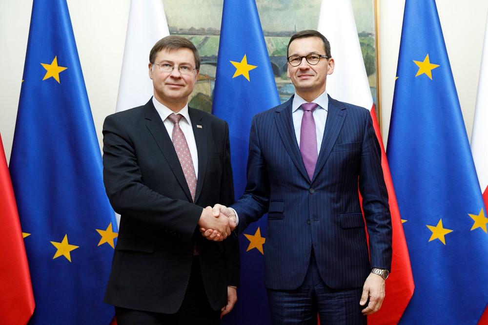 Premier Mateusz Morawiecki podczas uścisku dłoni z Valdisem Dombrovskisem