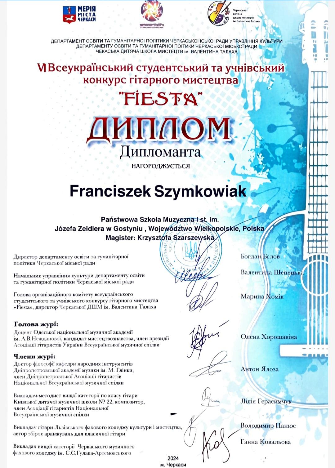 Dyplom ma biało - niebieskie tło. Z prawej strony znajduje się gitara. Do góry widać logo organizatorów. Z góry do dołu umieszczone są podpisy jurorów. 