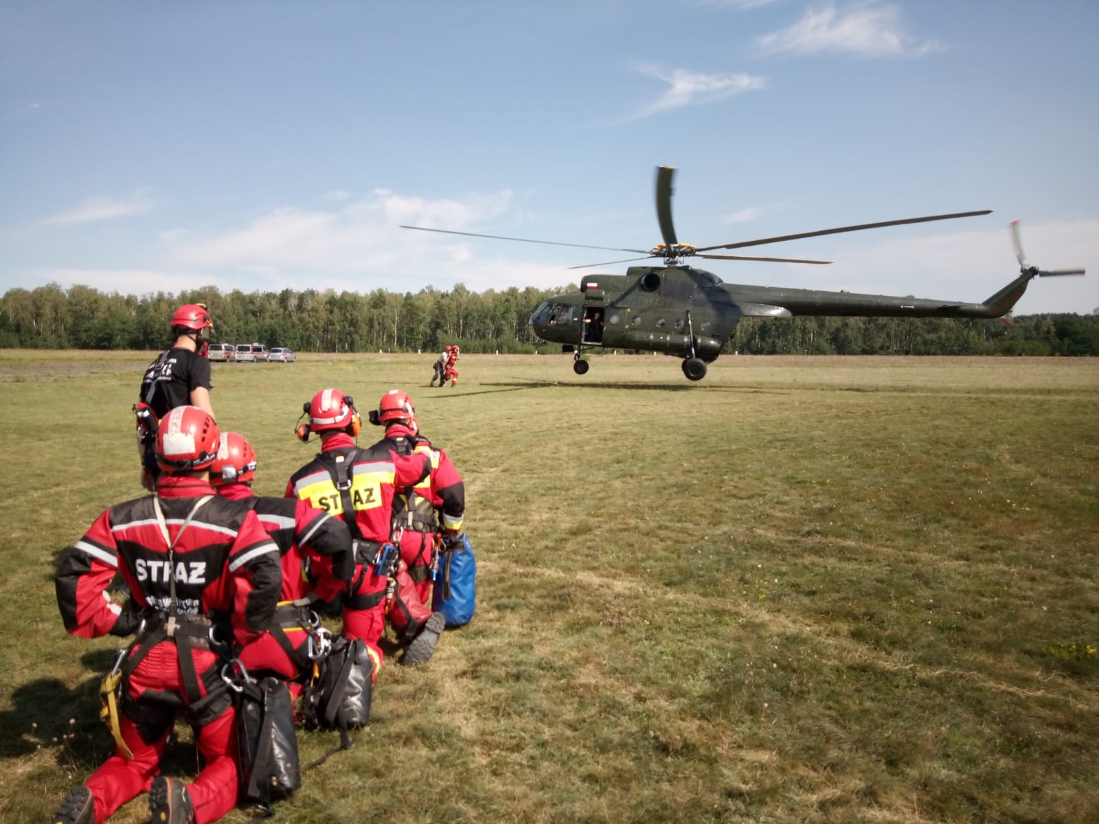 Strażacy na lądzie oczekują na podchodzący do lądowania śmigłowiec policyjny