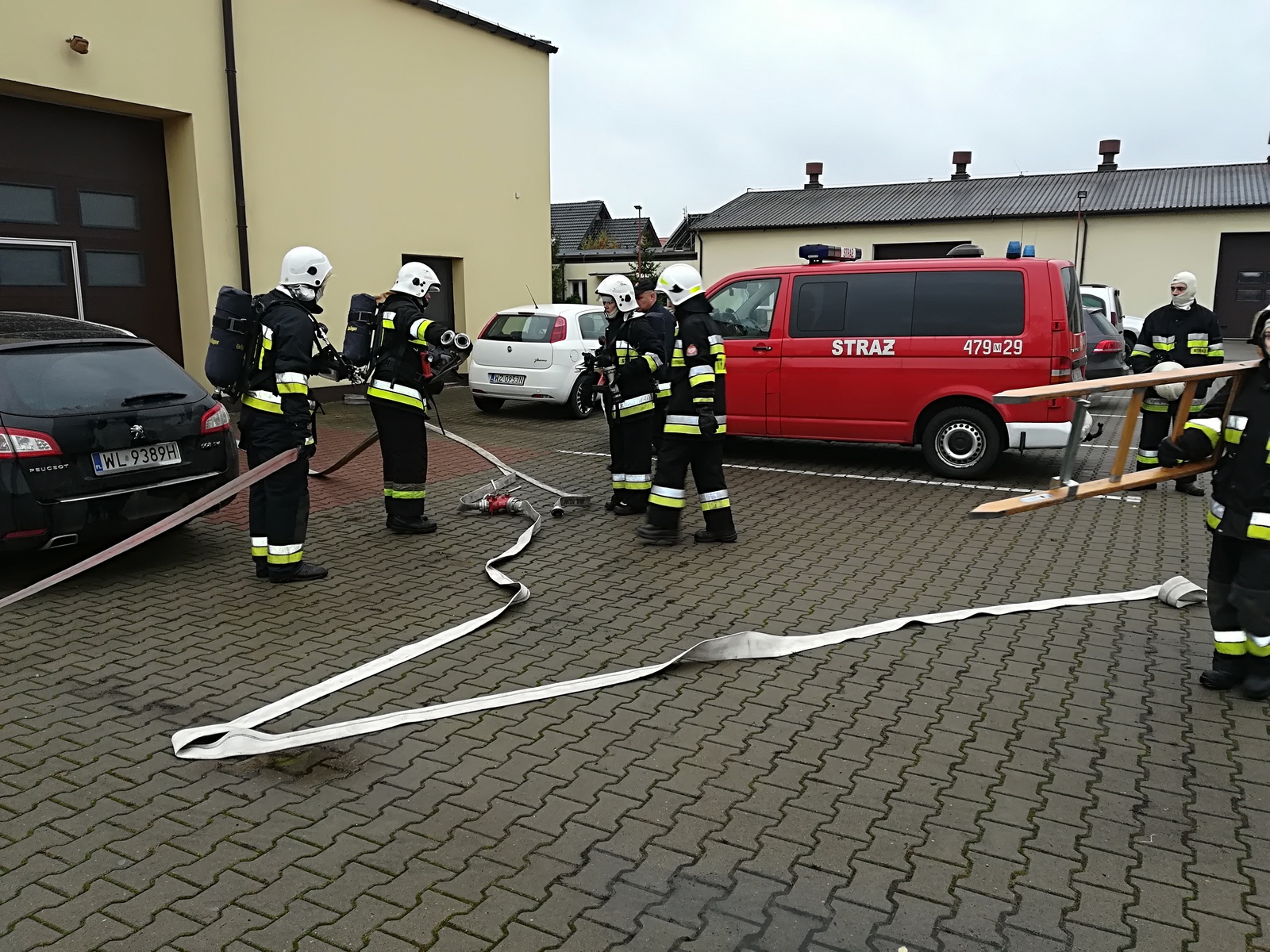 Zdjęcie przedstawia strażaków OSP podczas rozwijania linii wężowych w trakcie ćwiczenia.