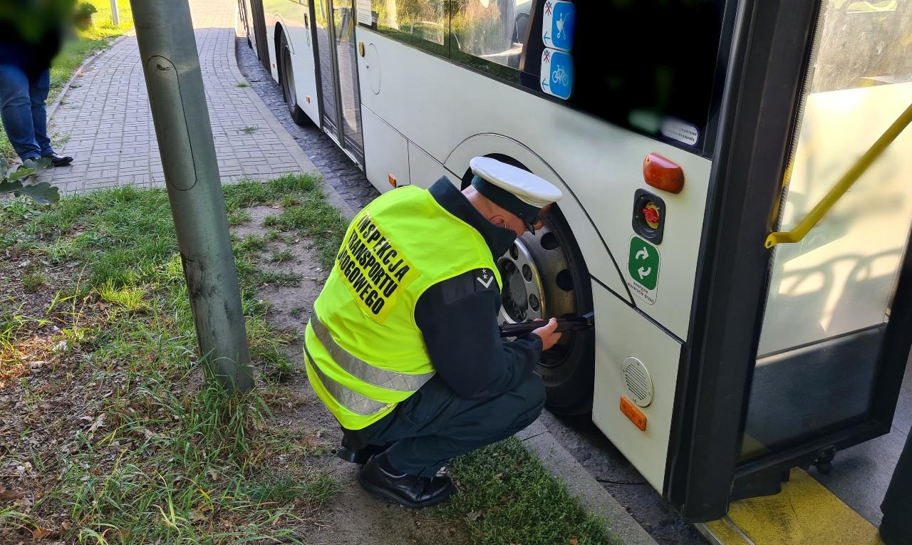 Inspektor ITD kontroluje ogumienie i układ kierowniczy autobusu miejskiego.