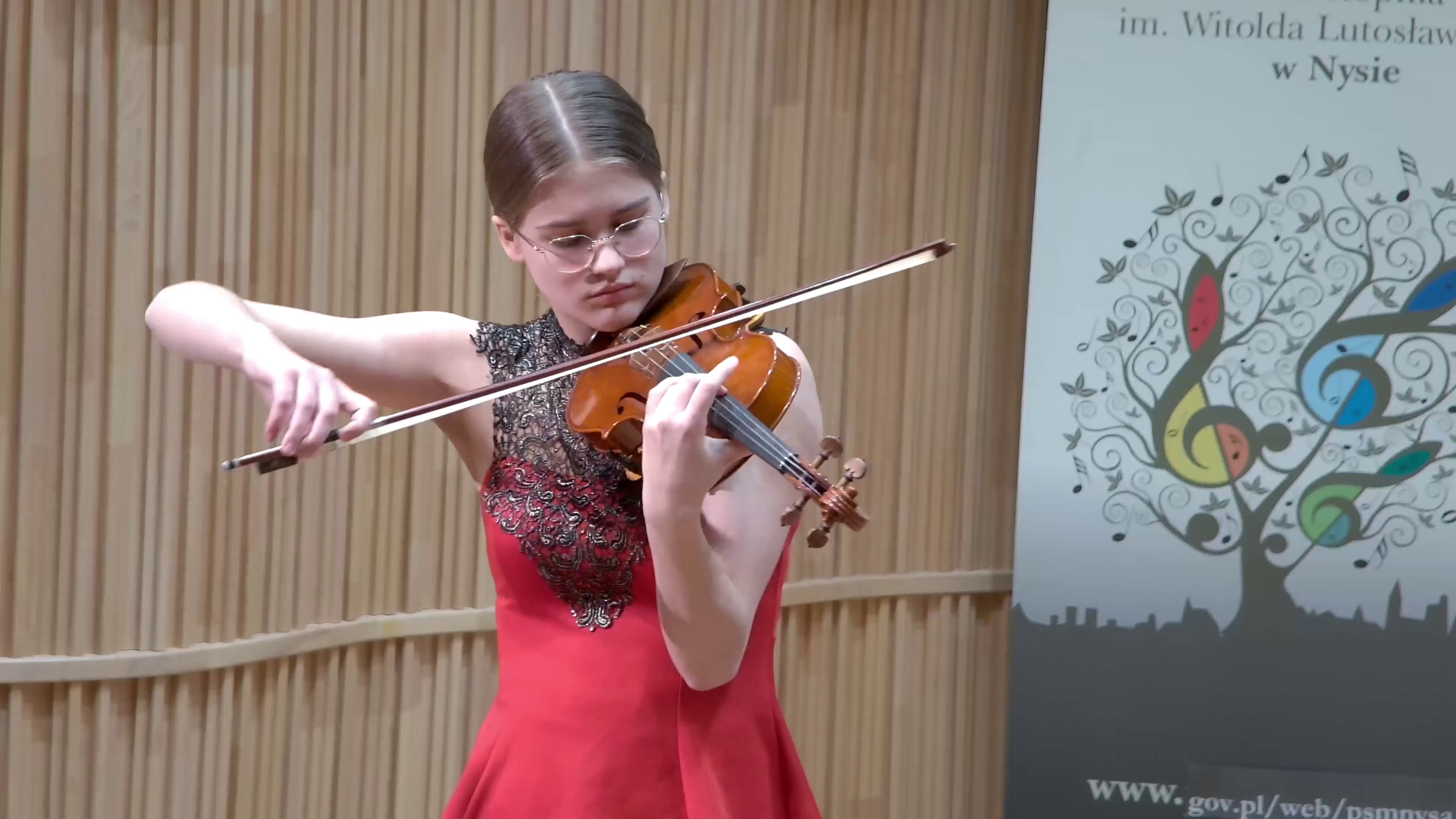 Zdjęcie. Na estradzie występuje skrzypaczka. W tle z lewej strony baner PSM Nysa.