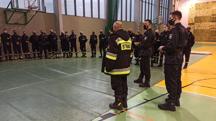 Wyjazd polskich strażaków na Słowację - odprawa na sali gimnastycznej. Strażacy w maseczkach. 