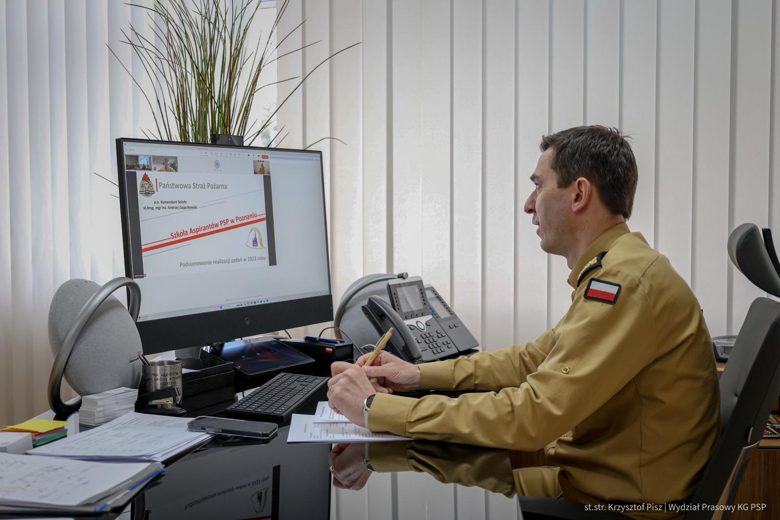 Komendant główny PSP siedzi przy biurku przed komputerem uczestnicząc w naradzie rocznej online
