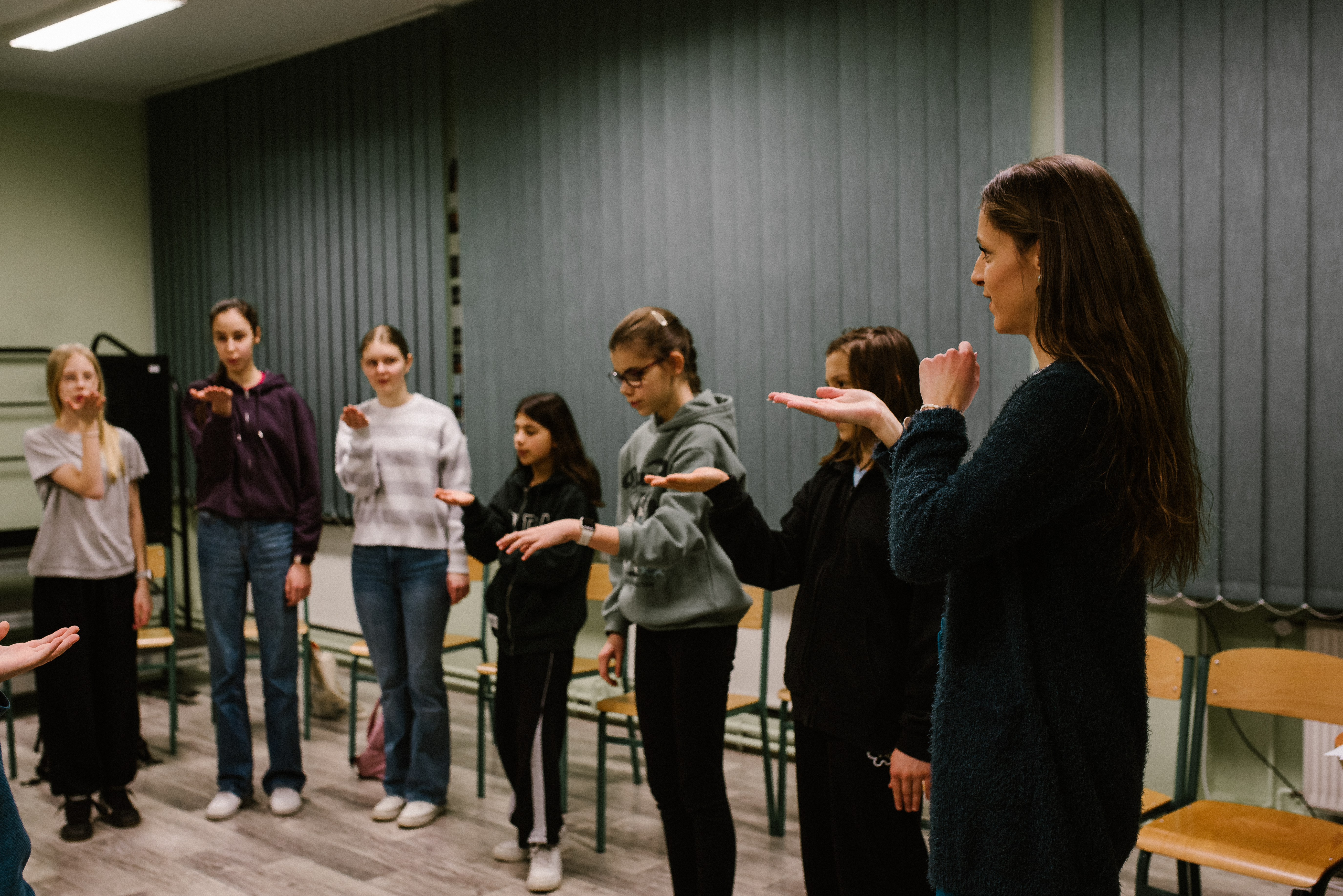 Na zdjęciu widoczna jest prowadząca zajęcia chóru oraz uczniowie.