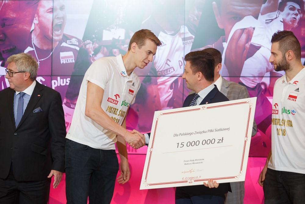 Minister Michał Dworczyk przekazuje czek od premiera siatkarzom.