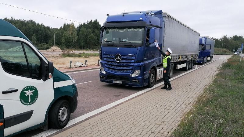 Inspektor ITD pobiera dokumenty od kierowcy ciężarówki.