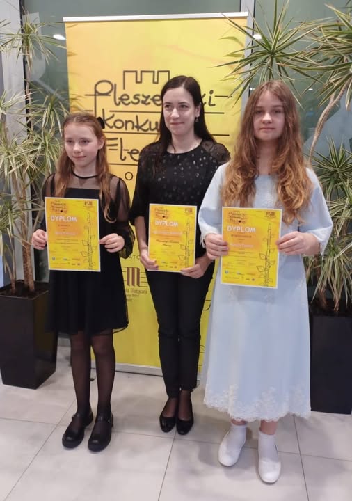 Na zdjęciu widoczne są dwie uczenice oraz nauczycielka fortepianu pełniąca funkcję akompaniatora. Wszystkie trzymają dyplomy konkursowe.