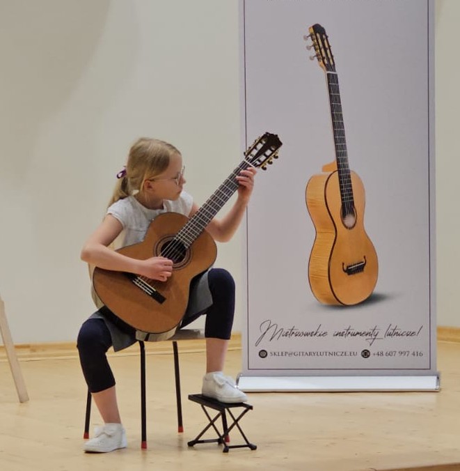 Uczennica Natalia Duślak na scenie z gitarą
