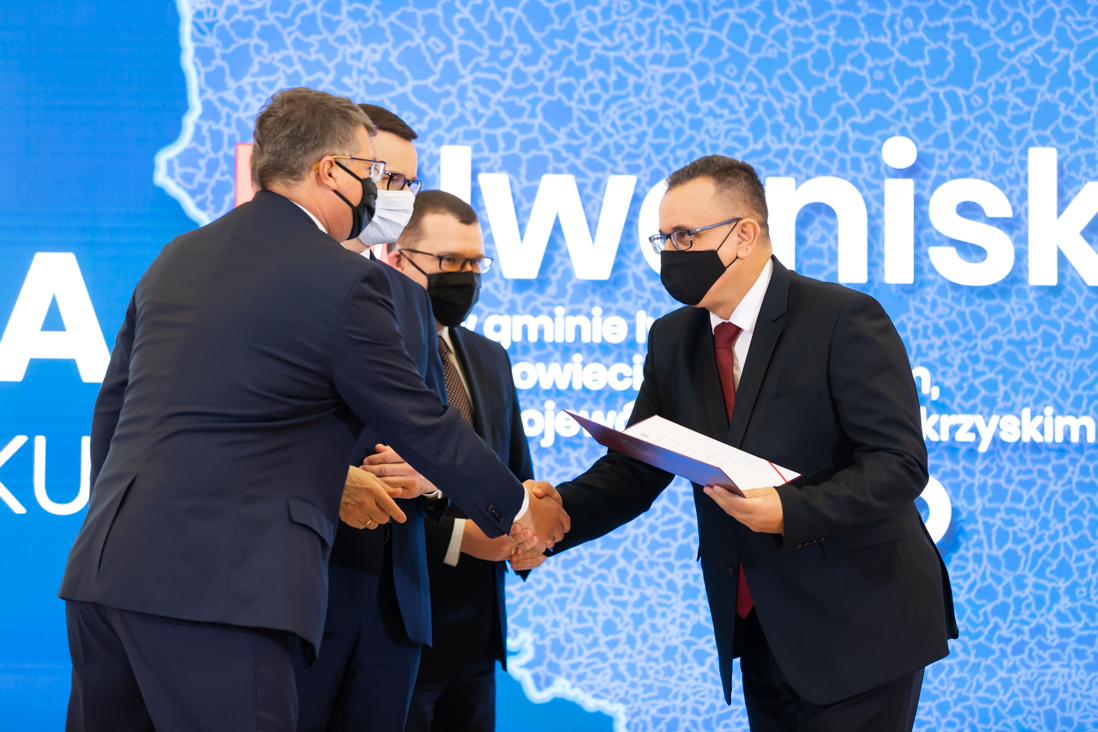 Na zdjęciu widać premiera Mateusza Morawieckiego, wiceministra Pawła Szefernakera i wiceministra Macieja Wąsika składającego gratulacje jednemu z przedstawicieli gmin która otrzymała akt nadania statusu miasta.