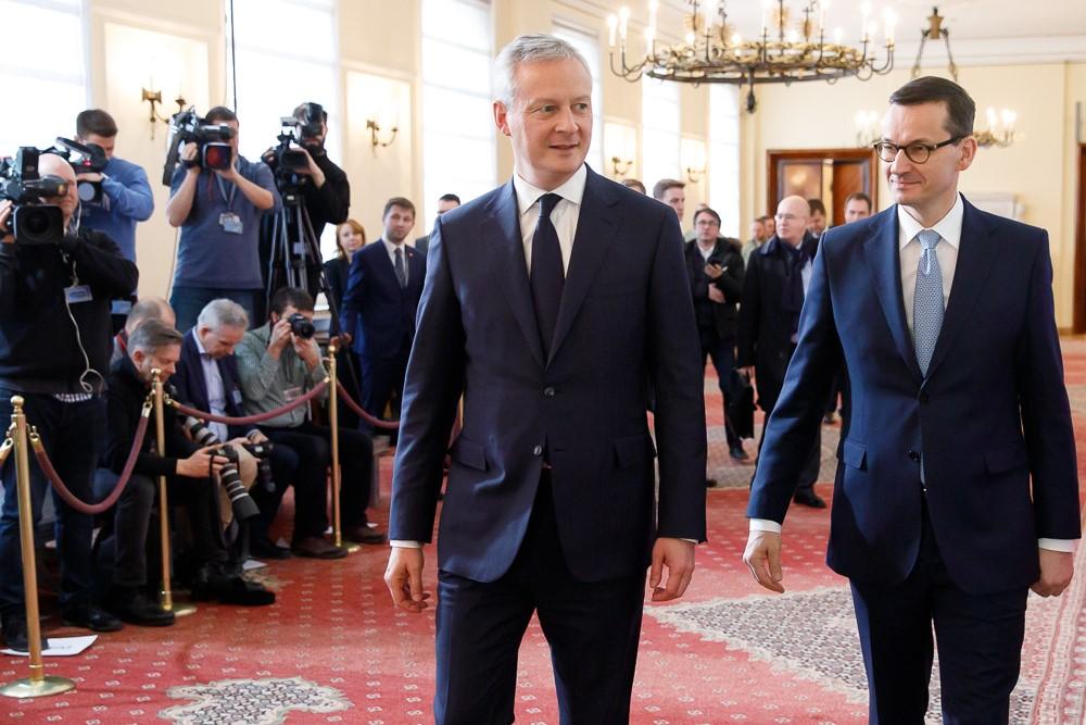 Premier Mateusz Morawiecki i Bruno Le Maire idą, a za nimi stoją dziennikarze.