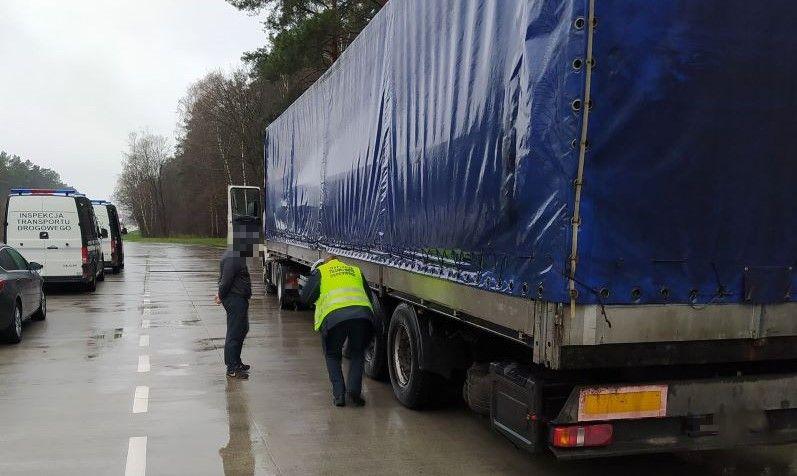 Inspektor kontroluje stan techniczny naczepy.