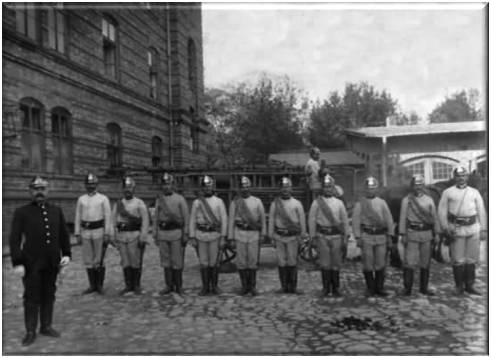 Pluton Miejskiej Zawodowej Straży Pożarnej, z lewej brandmistrz Wójcik. Fotografia z ok. 1900 r. 