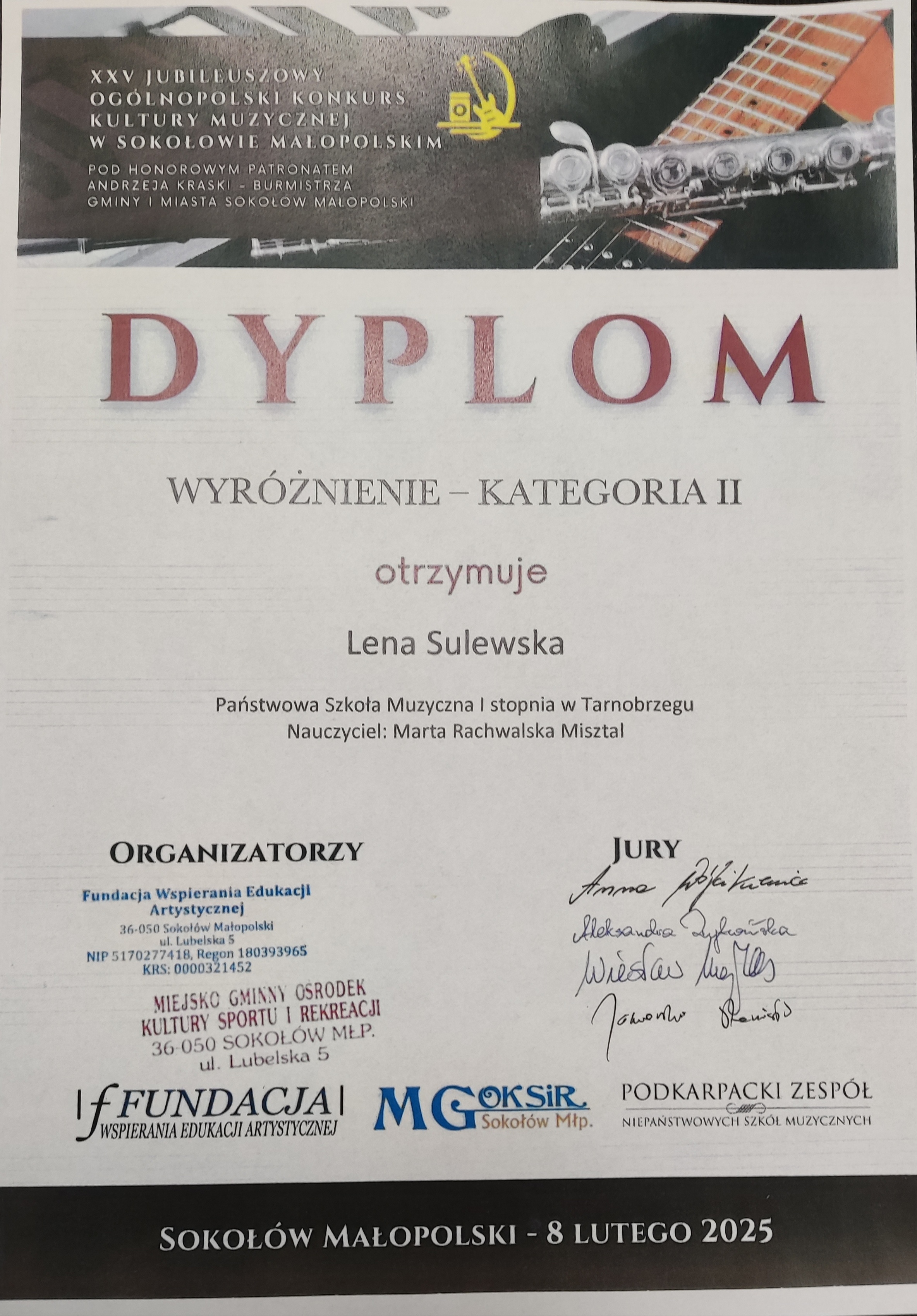 Dyplom wyróżnienia. Na górze znajduje się nazwisko patrona w brązowej ramce, a w tle zdjęcie przedstawiające fragmenty fortepianu, gitary oraz fleta poprzecznego. Po środku nazwisko otrzymującego wyróżnienie oraz nauczyciela. Na dole po lewej stronie organizatorzy, a po prawej podpisy jury. Tekst w kolorze czerwonym i czarnym.