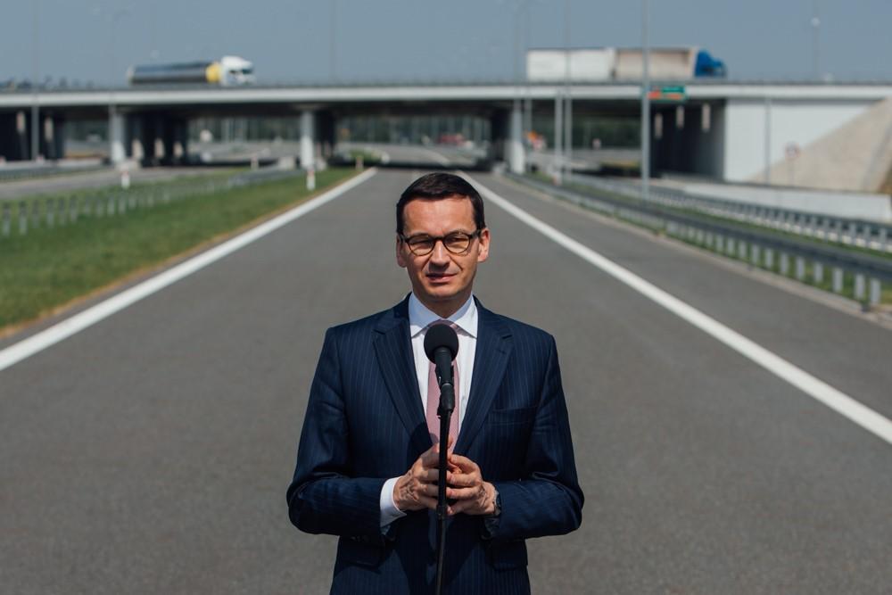Premier Mateusz Morawiecki na tle drogi.