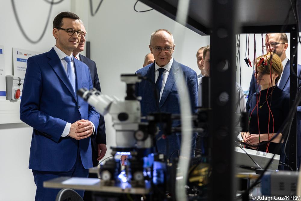 Premier Mateusz Morawiecki ogląda urządzenia i mikroskopy.