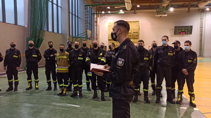 Wyjazd polskich strażaków na Słowację - odprawa na sali gimnastycznej. Strażacy w maseczkach.