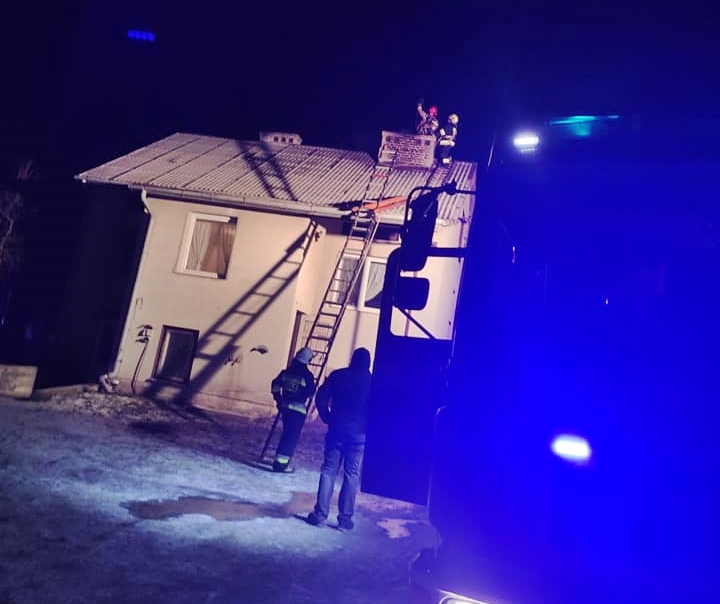 Pożar sadzy w budynku mieszkalnym. Na zdjęciu budynek mieszkalny, na dachu strażacy gaszą pożar sadzy w kominie.