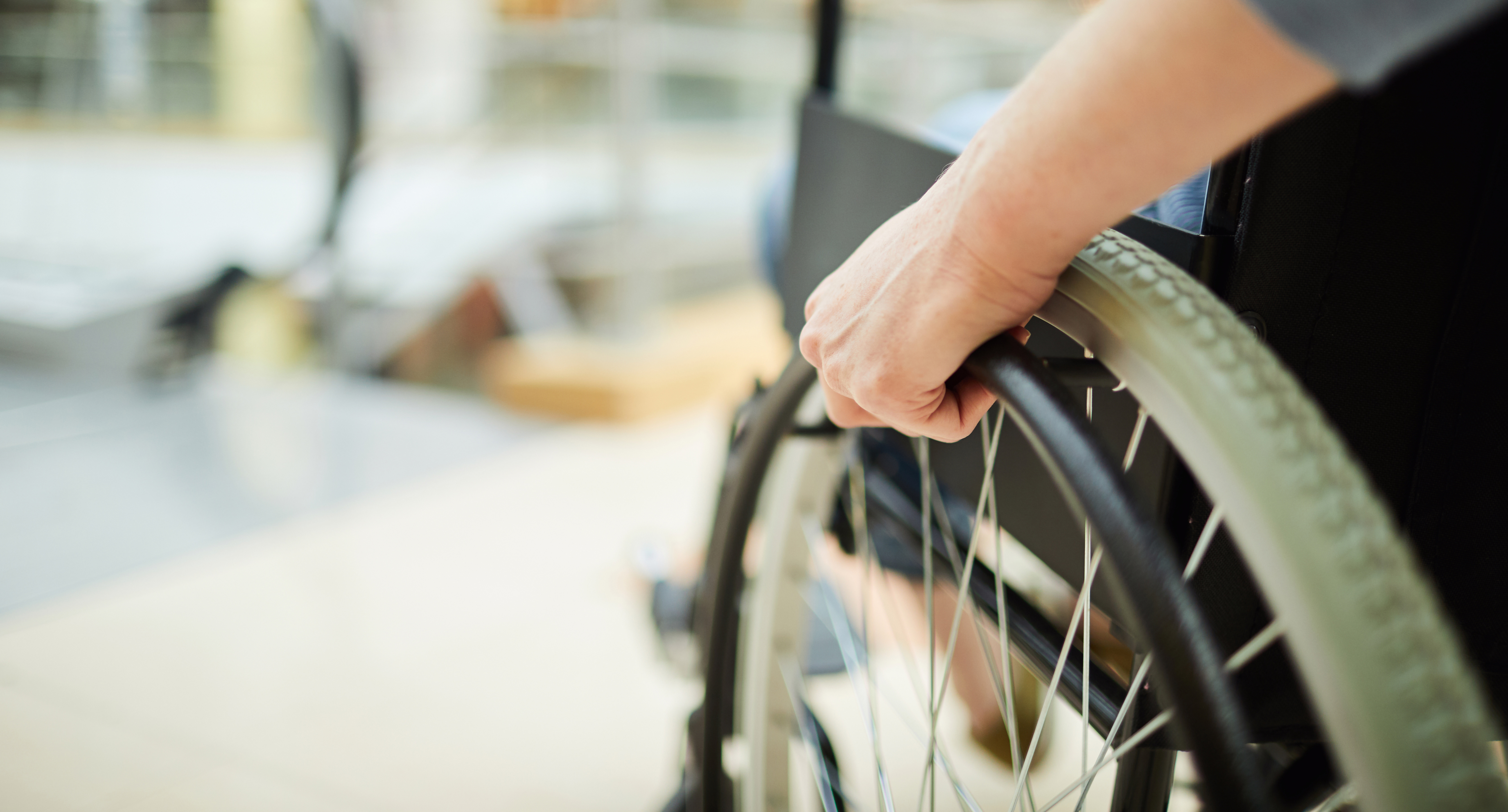 Lewa ręka trzyma koło wózka inwalidzkiego