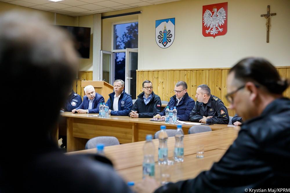 Premier Mateusz Morawiecki siedzi przy stole podczas odprawy - obok niego minister Szefernaker.