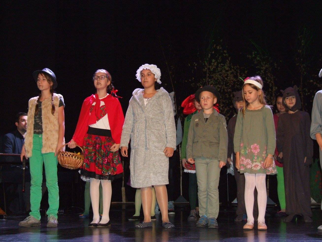 Zdjęcie przedstawia dzieci stojące w kilku rzędach. Mają na sobie różne przebrania, np. Czerwonego Kapturka, wilka, leśniczego.