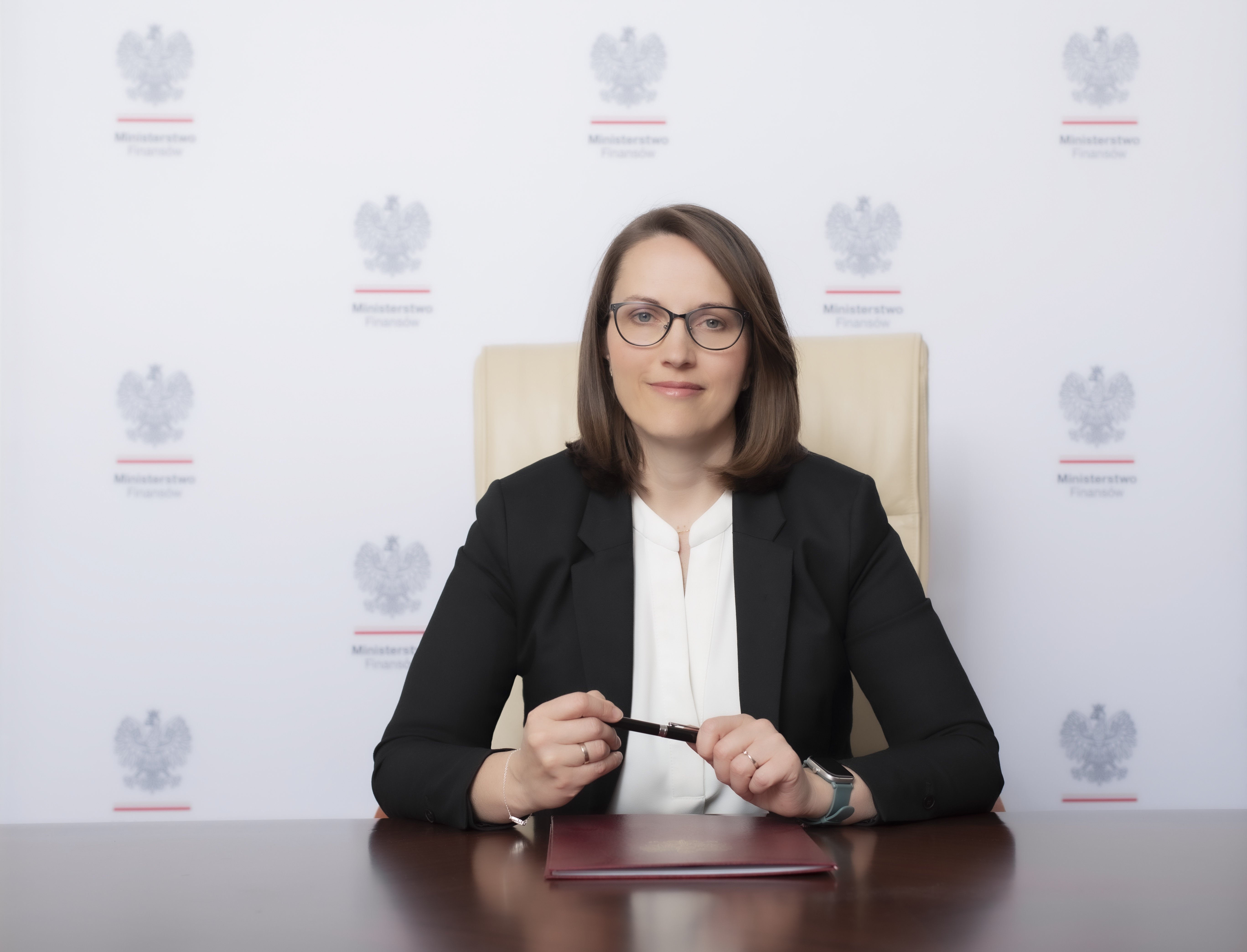 Minister finansów Magdalena Rzeczkowska - przy biurku, z piórem w rękach