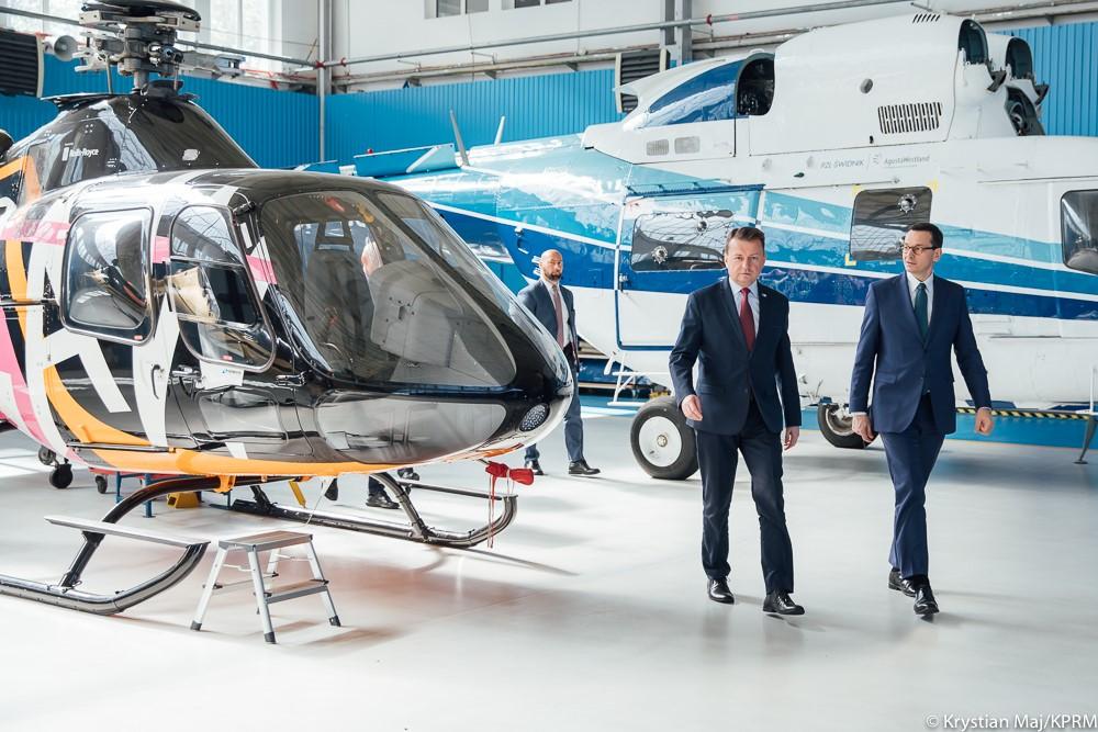 Premier Mateusz Morawiecki i minister Mariusz Błaszczak idą obok śmigłowca.