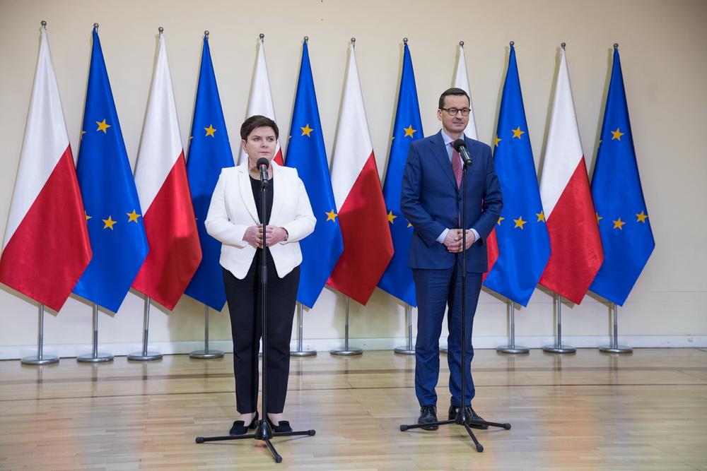 Premier Mateusz Morawiecki i wicepremier Beata Szydło podczas konferecji, a za nimi flagi Polski i Unii Europejskiej.