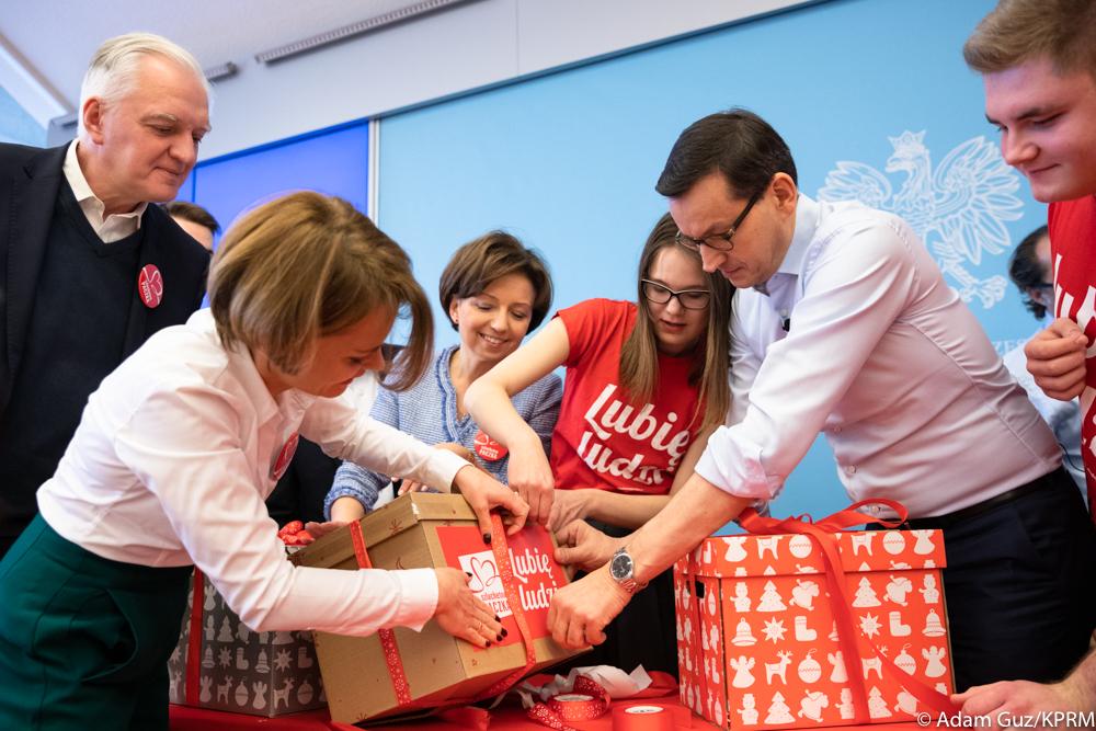 Premier Mateusz Morawiecki wraz z ministrami pakują paczkę.