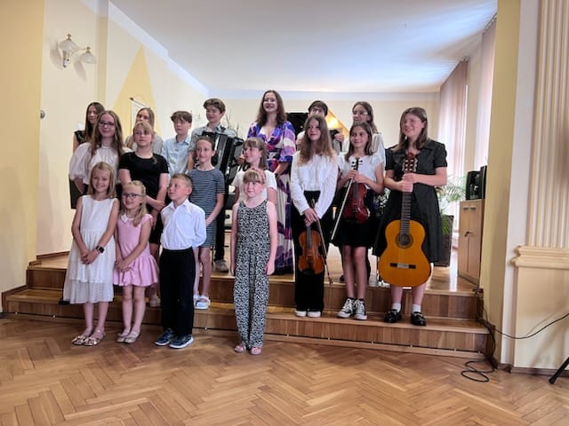 Grupa uczniów pozująca do zdjęcia grupowego podczas koncertu w auli w PSM w Kłodzku.
