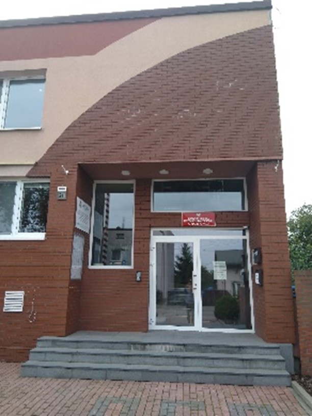 zdjęcie przestawia prawą część budynku komendy w której znajdują się drzwi główne do budynku do których prowadza trzy schody